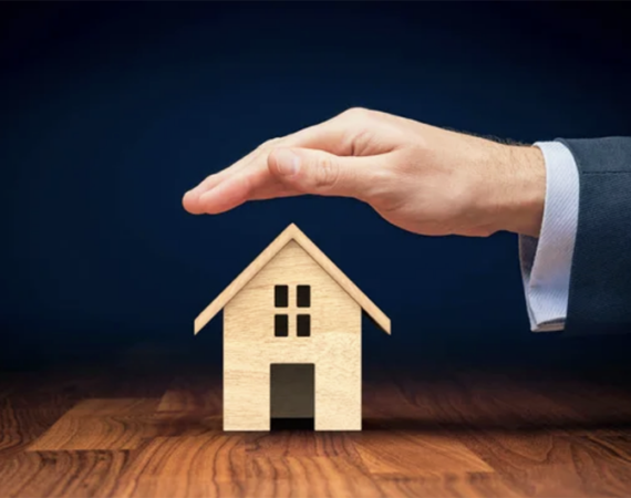 A hand covering a miniature house representing home insurance - 1 (800) 880-7954